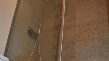 Ein Duschbereich mit Glasabtrennung, einer Dusche und einer Bedienkonsole.