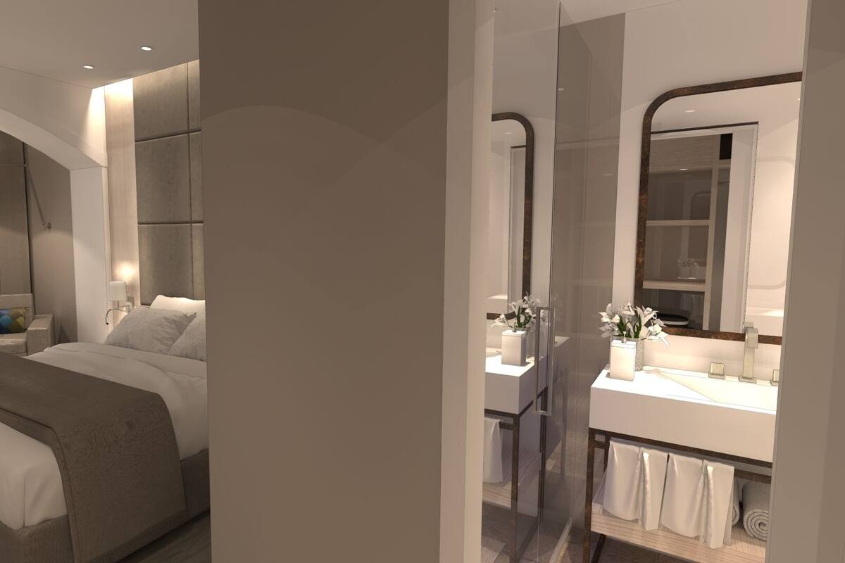 Un dormitorio moderno con una cama, una mesita de noche y otra mesita auxiliar.