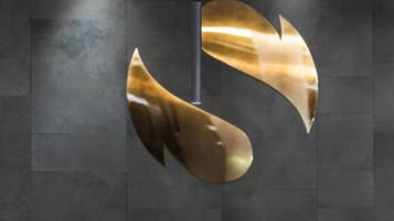 A wall with a large, abstract metallic sculpture.