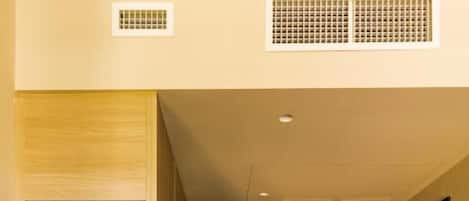 A hallway with a built-in wooden shelf unit, a refrigerator with beverages, and a door at the end.