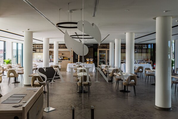 A spacious restaurant with high ceilings, modern furniture, and a central bar area.