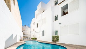 A modern white building with a swimming pool in the courtyard.