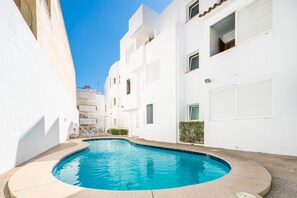 A modern white building with a swimming pool in the courtyard.