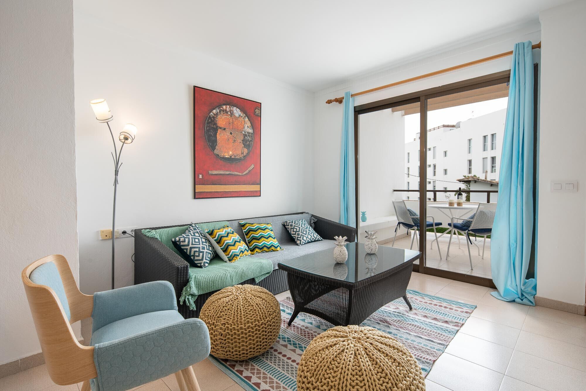 Una sala moderna con un sofá, una mesa de comedor y un balcón con sillas.