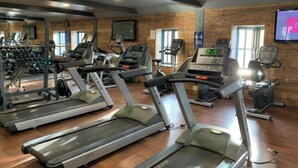 Et fitnessrum med løbebånd, styrkemaskiner og et spejl.
