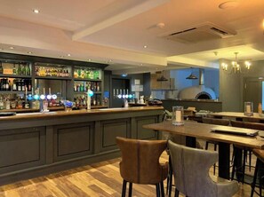 A bar area with a counter, shelves of bottles, and a seating area with tables and chairs. - Sandy Feet 1st floor apartment with open plan living on The Bay, Filey (Primrose Valley)