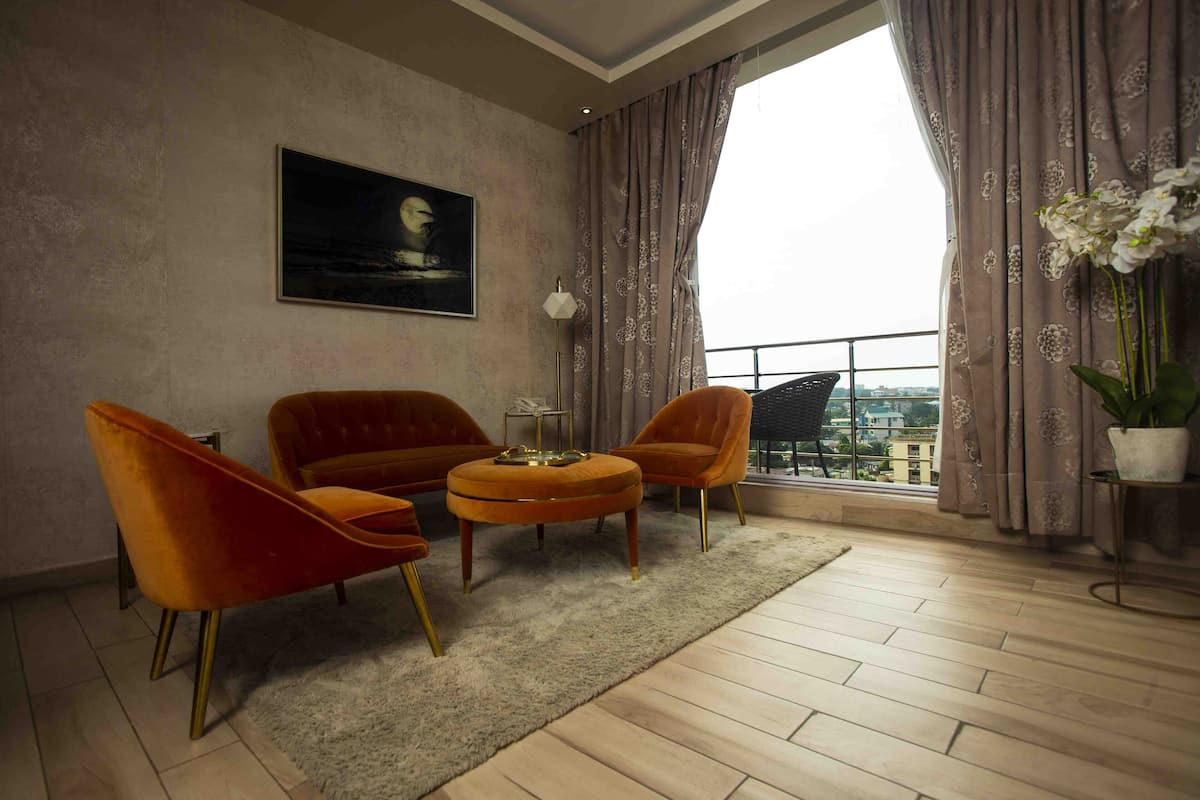A living room with a sofa set, a round coffee table, and a large window with curtains.
