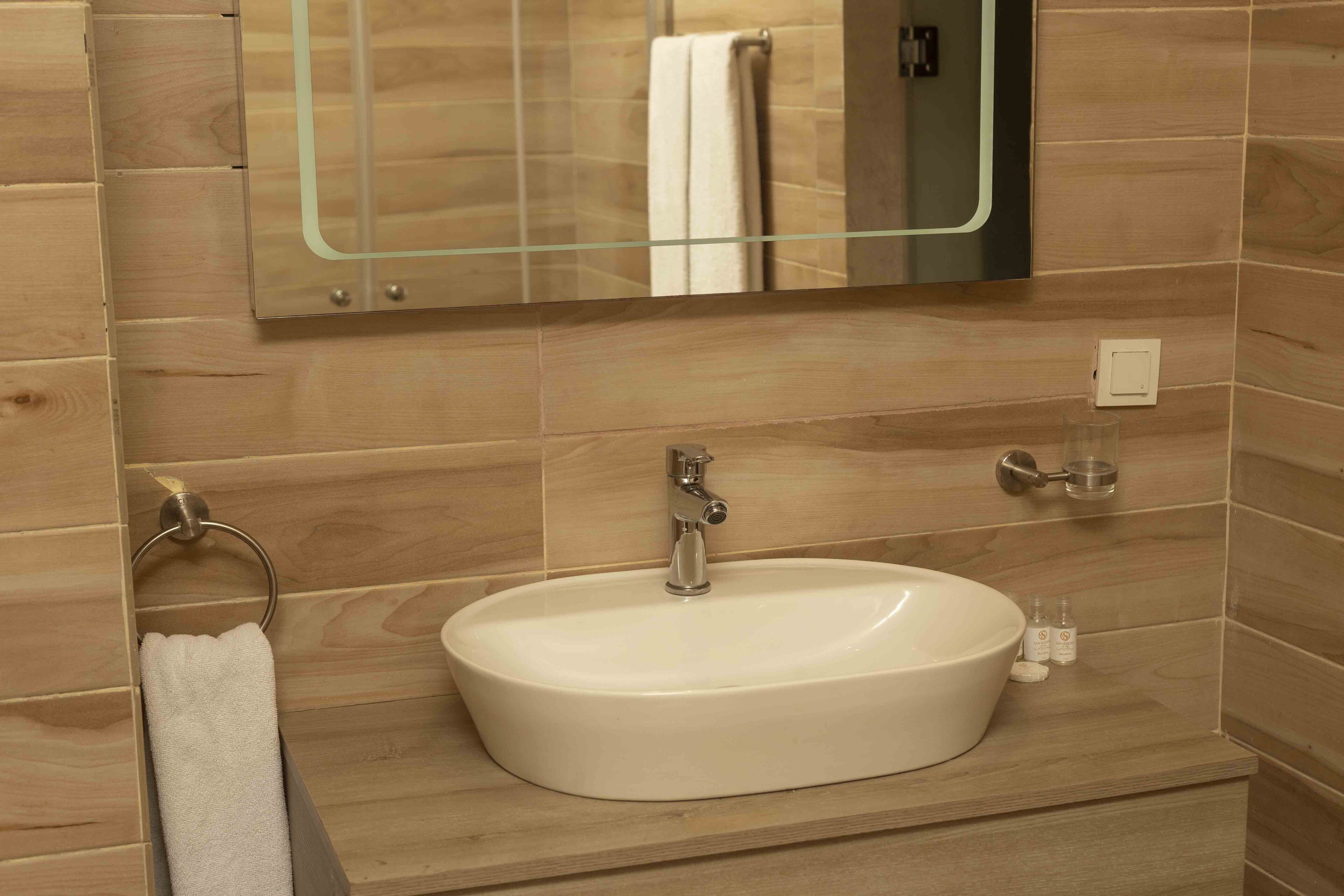 A bathroom with a white sink, a mirror, and a towel rack.