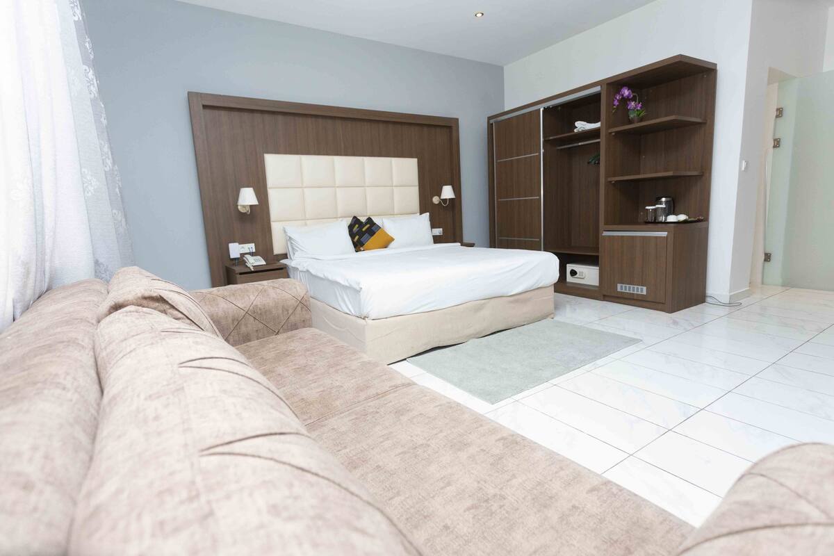 A bedroom with a bed, nightstands, a wardrobe, and a sofa.