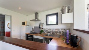 A compact kitchen with a dishwasher, stove, microwave, and a window above the sink.