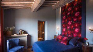 A bedroom with a large bed, a chair, a dresser, and a wall with a floral pattern. - Private villa with pool with panoramic view inside organic wine resort (Arezzo)