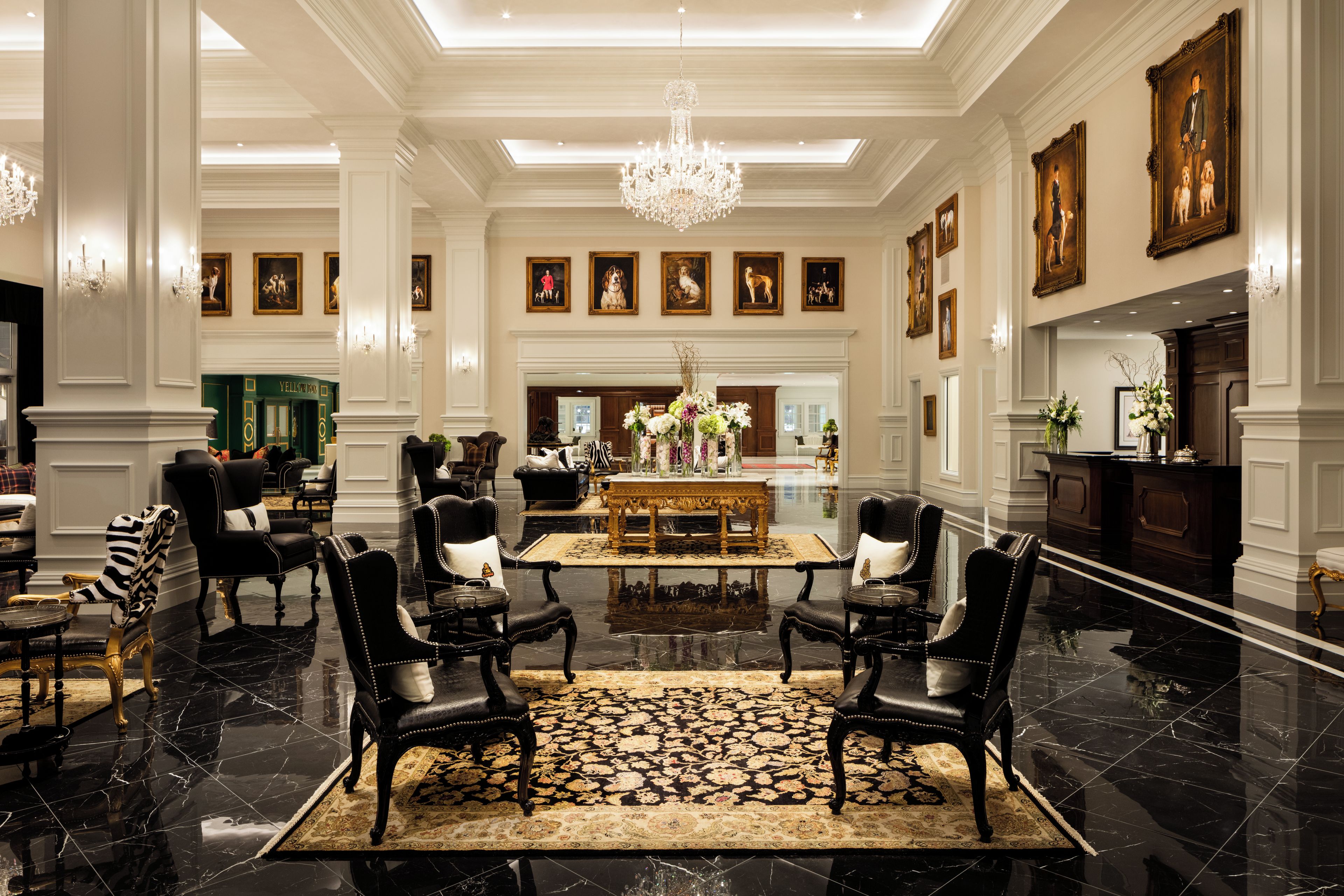 A spacious lobby with a chandelier, a fireplace, and a collection of framed artworks on the walls.