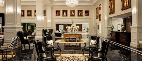 A spacious lobby with a chandelier, a fireplace, and a collection of framed artworks on the walls.