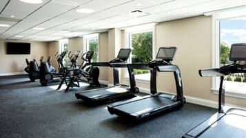 Une salle de sport équipée de tapis de course, de vélos elliptiques et de matériel de musculation.