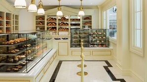 A bakery with shelves of baked goods, a glass display case, and a marble floor. - The Equestrian Hotel (Ocala)