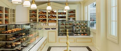 A bakery with shelves of baked goods, a glass display case, and a marble floor.