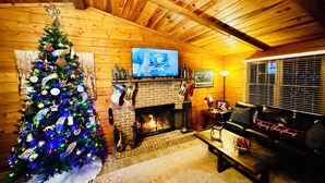 Un accogliente soggiorno con un albero di Natale decorato, un camino e un divano in pelle.