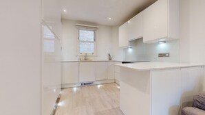 Een moderne keuken met witte kasten, een ingebouwde oven en een raam boven de gootsteen.