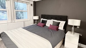 Een slaapkamer met een bed, twee nachtkastjes en een raam.