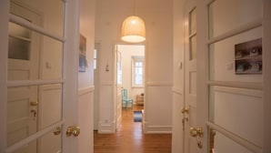 A hallway with white doors, a hanging pendant light, and a wooden floor. - Casa da Avenida I in Lisboa (Lisbon)