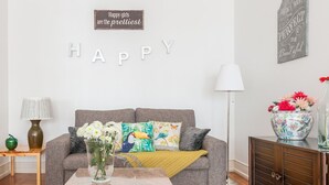 A living room with a grey sofa, a coffee table, a lamp, a vase with flowers, and a sign on the wall. - Casa da Avenida I in Lisboa (Lisbon)