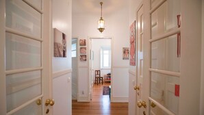 A hallway with white doors, a wooden floor, and a hanging light fixture. - Casa da Avenida III (Lisbon)