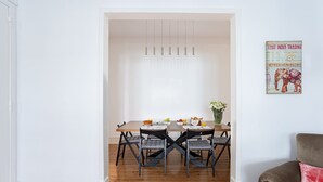 Un comedor con una mesa de madera, cuatro sillas y lámparas colgantes.