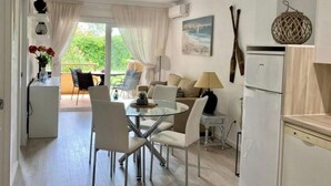 A modern kitchen with white appliances, a dining area with a glass table, and a balcony with outdoor seating. - Stil Mar Anna 300 m from the sea Salted swimming pool, garden, private terrace in Léscala (L'Escala)