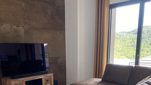 Ein modernes Wohnzimmer mit einem großen Flachbildfernseher, einem braunen Sofa und einer Holz-Unterhaltungsecke.