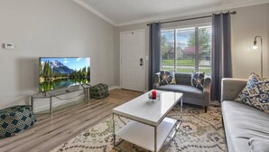 A modern living room with a flat-screen TV, a sofa, a coffee table, and a patterned rug. - Easy Livin` By Easton: Hot tub, Family Friendly, 6 minutes from Easton Town Center (Columbus)
