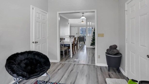 A hallway with a black chair, a trash bin, and a dining area in the background. - Easy Livin` By Easton: Hot tub, Family Friendly, 6 minutes from Easton Town Center (Columbus)