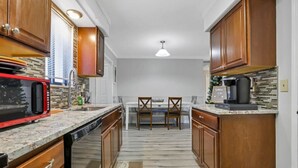 A kitchen with wooden cabinets, a microwave, a coffee maker, and a dining table with chairs. - Easy Livin` By Easton: Hot tub, Family Friendly, 6 minutes from Easton Town Center (Columbus)