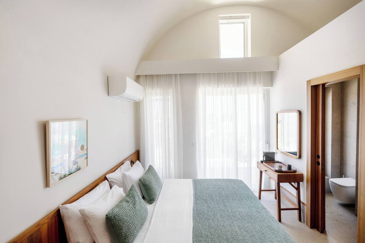 A bedroom with a bed, bedside table, and a window.