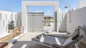 A rooftop terrace with a pool, lounge chairs, and a view of the landscape.