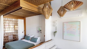 A bedroom with a bed, bedside tables, a sofa, and a hanging light fixture.