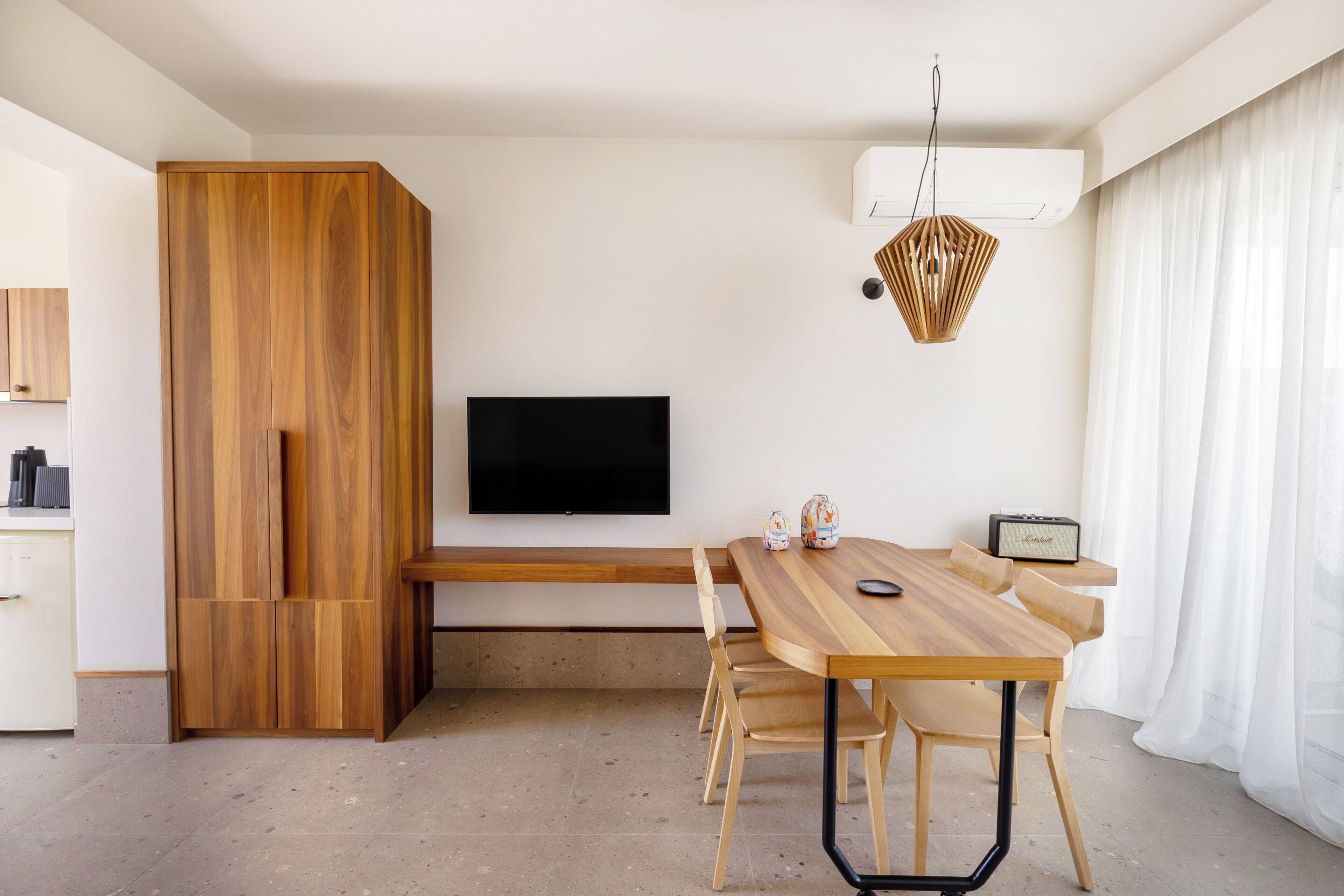 Una sala de estar moderna con una mesa de comedor de madera, un televisor de pantalla plana y un banco empotrado.