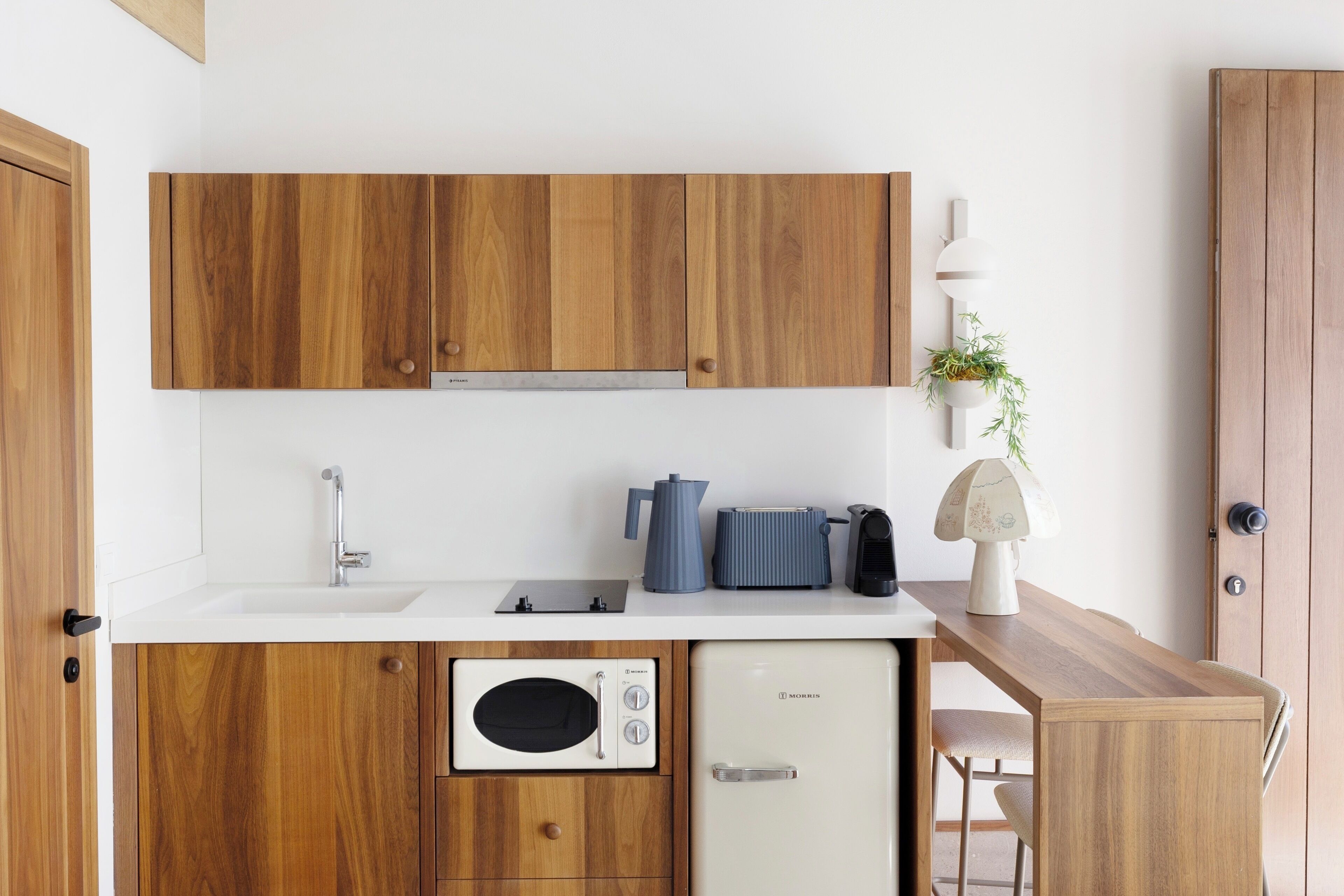 A compact kitchen with wooden cabinets, a built-in microwave, a coffee maker, and a small refrigerator.