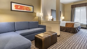 A hotel room with a sofa, ottoman, bed, and a large mirror. - Chic hotel with AC and fitness room in marvelous Houston (Houston)