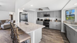 A modern kitchen with granite countertops, stainless steel appliances, and a large island with bar stools. - SEASIDE VILLA MANATEE BAY in quiet location on Pine Island (Saint James City)