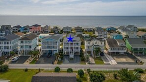 Een kustwoongebied met een rij huizen, een opvallend blauw sterrensymbool en uitzicht op de oceaan.