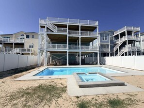 Un edificio de varios pisos con un área de piscina, que incluye un jacuzzi y una piscina.