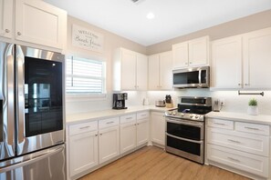 Enjoy cooking in this well-equipped kitchen with a refrigerator, oven, and microwave, along with ample countertop space.