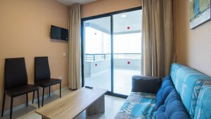 Ein modernes Wohnzimmer mit einer Couch, zwei Sessel, einem Tisch und einer Schiebetür zu einem Außenbalkon.