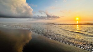 Une plage au coucher du soleil, où les vagues viennent doucement lécher le rivage.