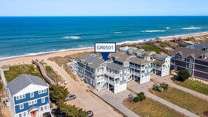 Il s’agit d’un quartier résidentiel situé sur la côte, où se trouve un immeuble bleu imposant, portant la mention GR0501, avec de nombreux étages et balcons, et qui est adjacent à une plage et à l’océan.