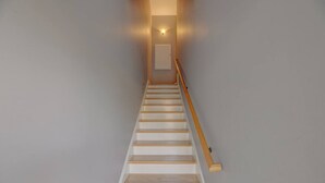 Un escalier avec des marches en bois et une rampe, menant à une porte située en haut.