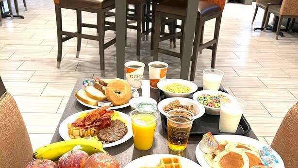 A breakfast table with various food items including waffles, pancakes, eggs, and fruit. - Comfort Suites Near Sam Houston Race Park (Houston)
