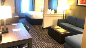 A hotel room with a bed, a sofa, a desk with a lamp, and a small table. - Comfort Suites Near Sam Houston Race Park (Houston)