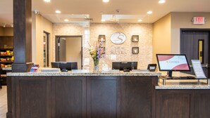 A hotel reception desk with a computer monitor displaying 'Choice Hotel' branding, a 'COMFORT SUITES' sign, and a security camera above the desk. - Comfort Suites Near Sam Houston Race Park (Houston)