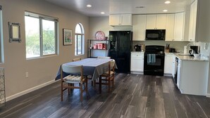 Une cuisine moderne avec des meubles blancs, un réfrigérateur noir et un coin repas comprenant une table et des chaises.